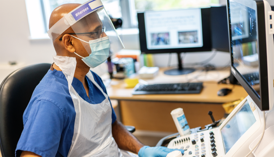 Health and wellbeing - man at computer in PPE 